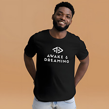 The black Logo Tee worn, smiling, on a warm studio backdrop